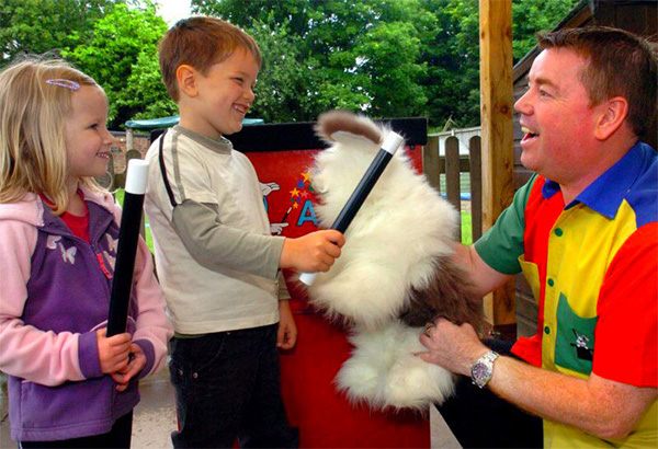 Magician performs with children in magic show